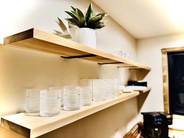 A shelf with a potted plant and several glass containers.