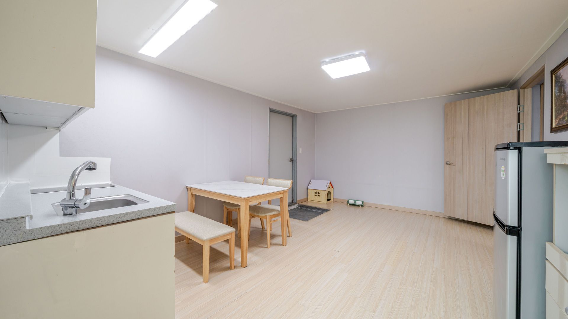 A compact kitchen with a dining area, a small playhouse, and a refrigerator.