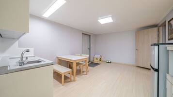 A compact kitchen with a dining area, a small playhouse, and a refrigerator.