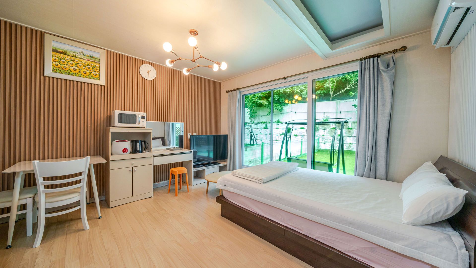 Habitación de hotel con cama, escritorio, silla, televisor y vista al exterior.