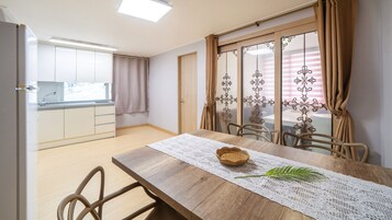 Un comedor con una mesa de madera, sillas y vistas a la cocina y al balcón.