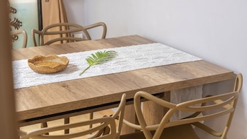Una mesa de madera con un mantel de encaje, una cesta tejida y una hoja verde.