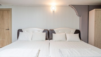Una cama doble con cabecera, una puerta de madera y un accesorio de iluminación en la pared.