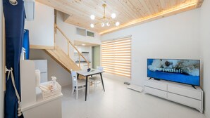 Een moderne woonkamer met een televisie, een eethoek en een trap.