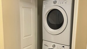 A laundry room with two stacked front-loading washing machines and a bottle of detergent on top. - Two Bedroom, Two Bath Condo ready for year-around fun. Great Up North Getaway! (Bellaire)