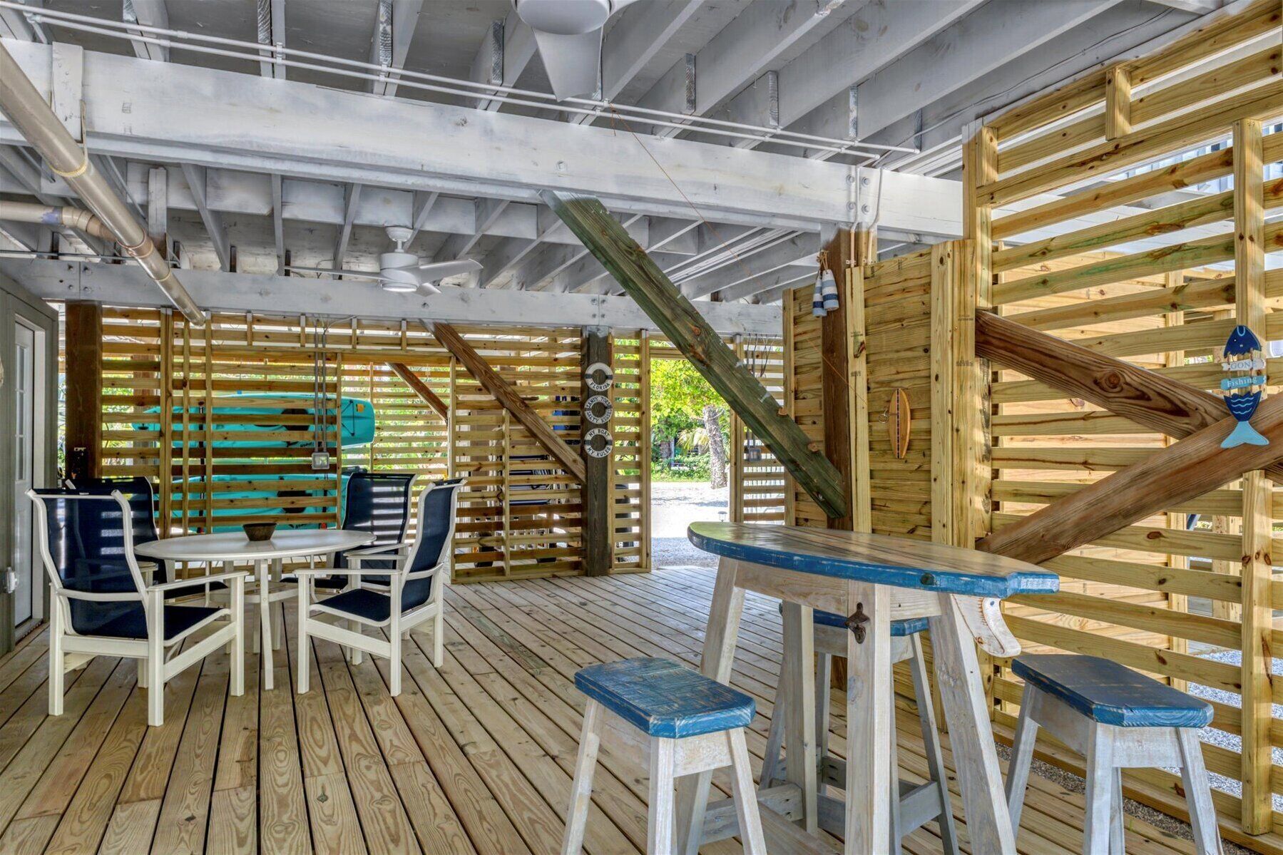 Un patio esterno in legno con tavolo e sedie, circondato da listelli di legno e una scala.