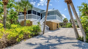 A two-story beachfront property with a wooden deck and a balcony.