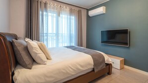 A modern bedroom with a bed, curtains, an air conditioning unit, and a mounted TV.