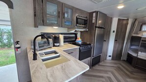 A compact kitchen with a microwave, refrigerator, toaster, and sink. - Country Cowboy RV Campsite in River Ranch 72 (River Ranch)