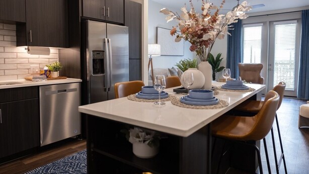Een moderne keuken met donkere kastjes, roestvrijstalen apparatuur en een centraal eiland met blauw-witte decoratie.