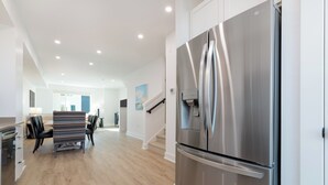A modern kitchen with a stainless steel refrigerator, wooden flooring, and a dining area with a table and chairs. - Charming 3 bed townhome w/direct access to downtown GJ! NO EXTRA FEES! (Grand Junction)