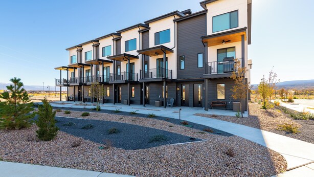 A modern multi-story residential building with balconies, a landscaped garden, and a clear view of the surrounding landscape. - Charming 3 bed townhome w/direct access to downtown GJ! NO EXTRA FEES! (Grand Junction)