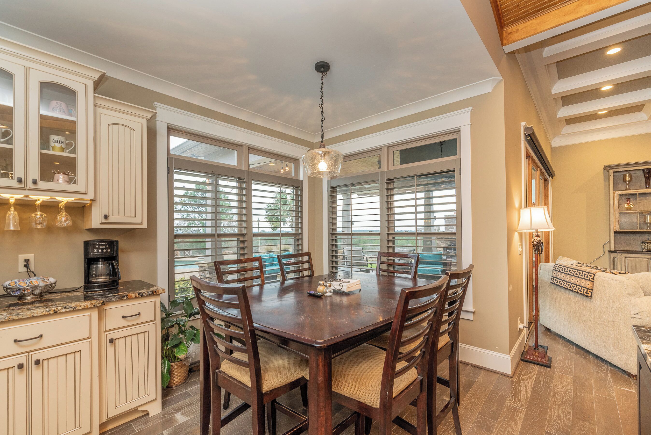 A dining area with a wooden table and chairs, a coffee maker, and a chandelier.