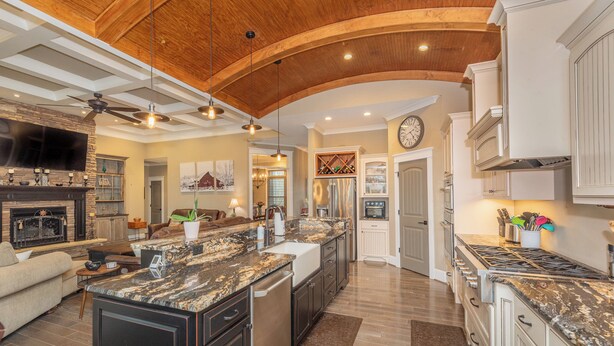 A spacious kitchen with granite countertops, a large island, and a wooden ceiling.