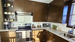 Eine moderne Küche mit Edelstahlgeräten, Holzschränken und einer Arbeitsplatte aus Granit.
