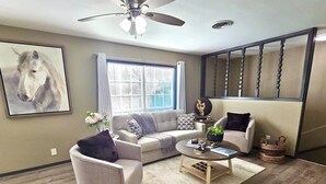 Ein Wohnzimmer mit Sofa, Sessel, Couchtisch und Deckenventilator.