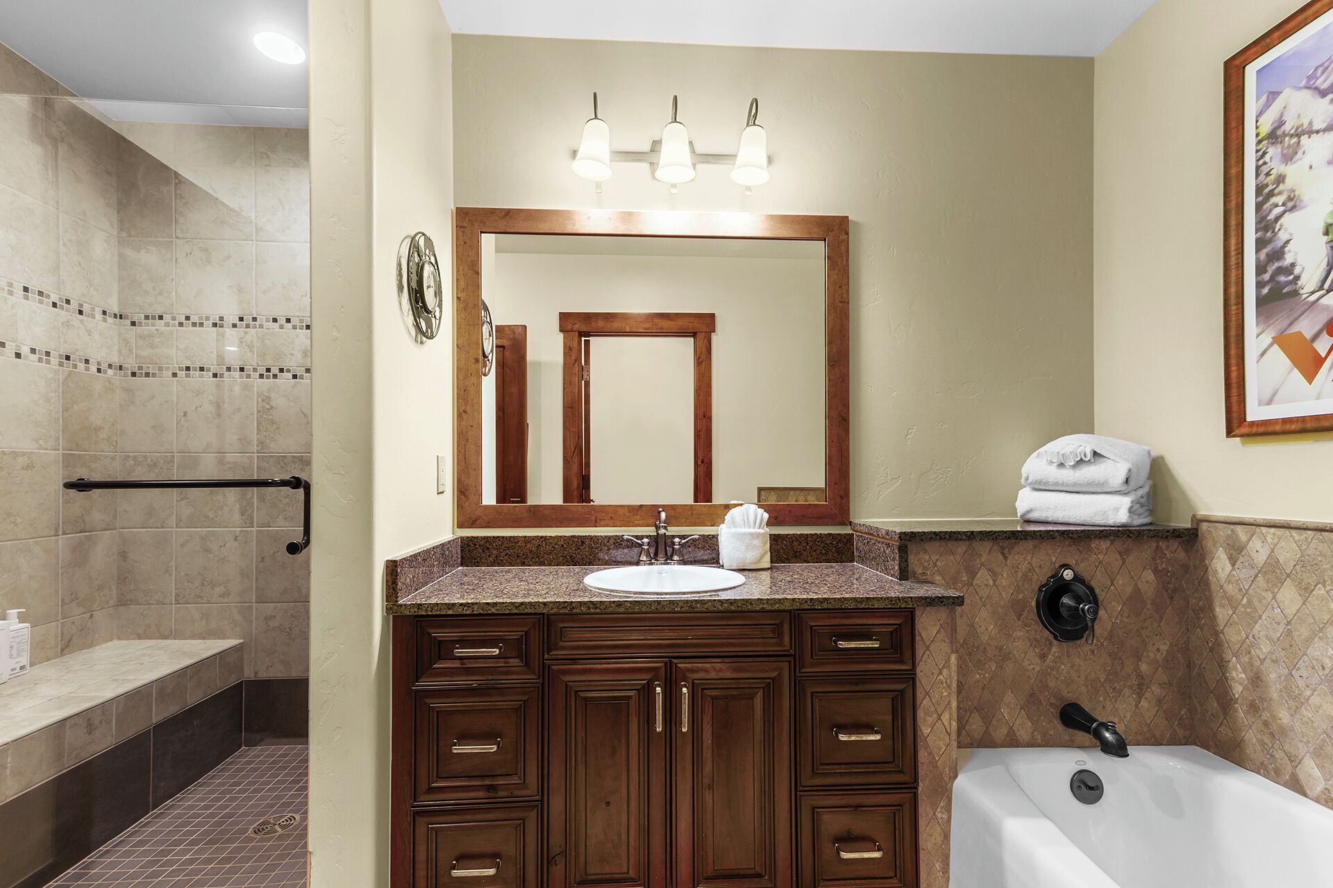 Une salle de bain équipée d’un lavabo, d’un meuble-lavabo, d’un miroir et d’une baignoire.