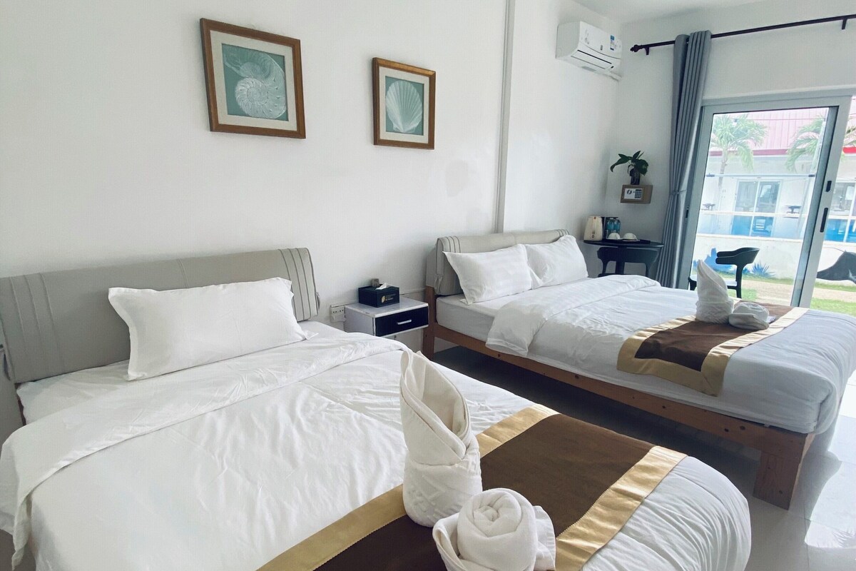 Een hotelkamer met twee bedden, een groot raam en uitzicht op buiten.