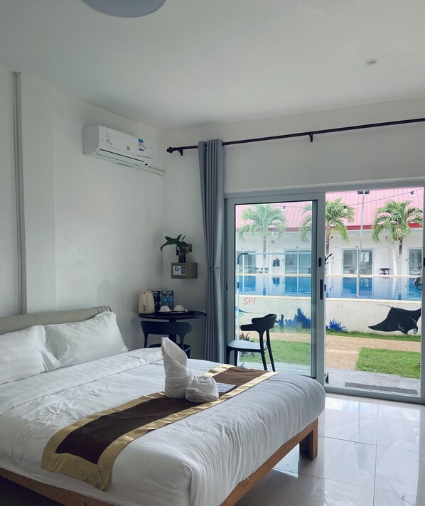 A hotel room with a large bed, a desk, a chair, and a view of the outside. - Green Mango Resort (Panglao)