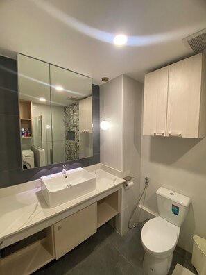 Ein modernes Badezimmer mit Waschbecken, Spiegel und Toilette in Weiß.