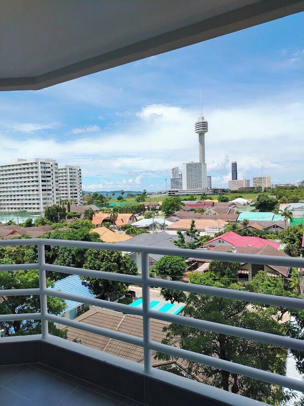 Ein Balkon mit Blick auf eine Stadtlandschaft, darunter ein hoher Turm und Wohnhäuser.