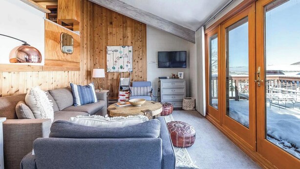 Un salón acogedor con pared de madera, un sofá, una mesa de centro y un televisor.