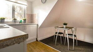 Een moderne keuken met een raam, een klok en een eethoek met stoelen en een tafel.
