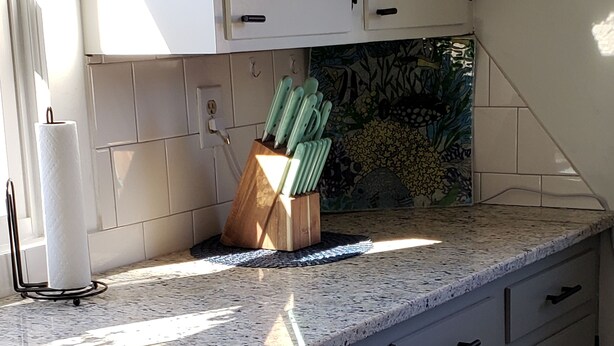 Eine Küche mit weißen Schränken, einer Granitarbeitsplatte und einem Messerblock.