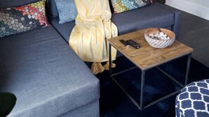 Ein modernes Wohnzimmer mit einer Eckcouch, einem Couchtisch und einem dekorativen Spiegel.
