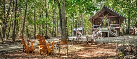 A cabin in a forest with outdoor seating and a deck.