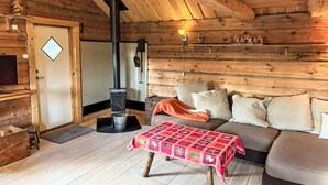 Interior acolhedor de uma cabana de madeira, com decoração em madeira, lareira, sofá e uma mesa com toalha festiva.