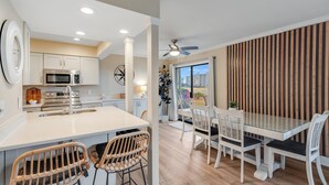 A modern kitchen with white cabinetry, stainless steel appliances, and a central island with bar stools.