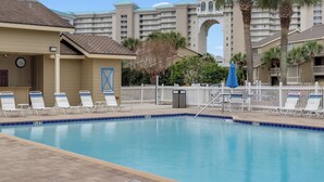 A swimming pool with lounge chairs, a clock, and a white picket fence.