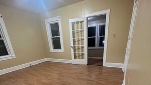 A room with wooden flooring, a vent, and two doors with glass panels. - Karan luxury apartment (Jersey City)