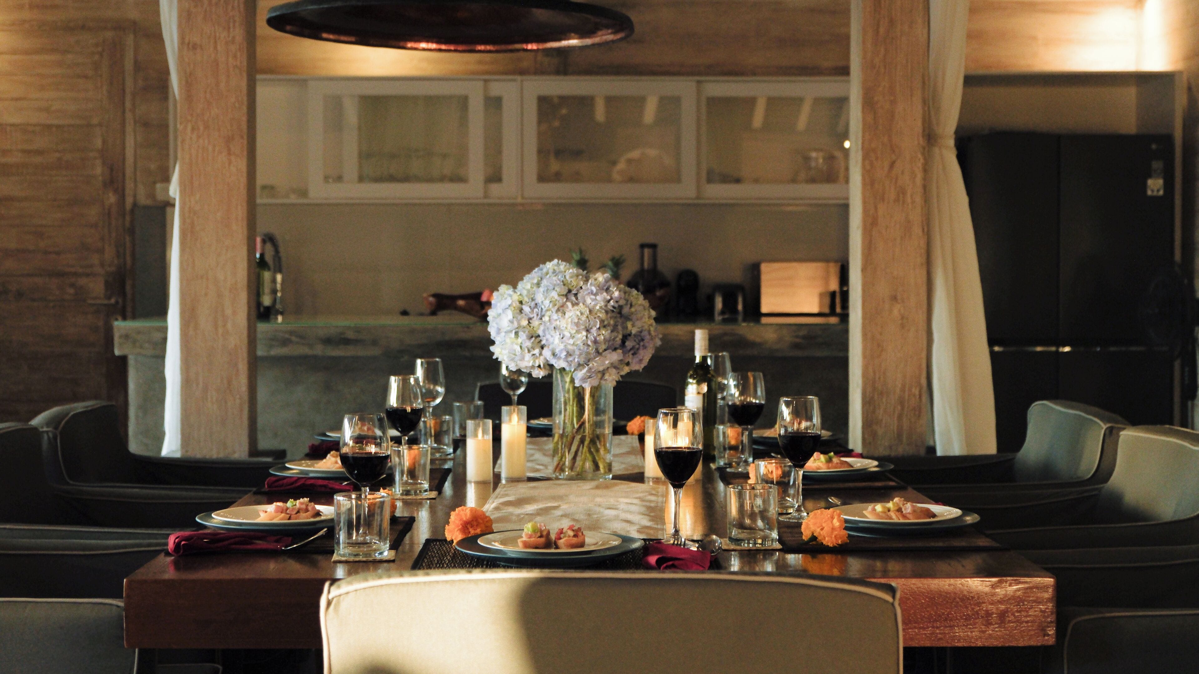 A dining table set with wine glasses, plates, and a centerpiece of flowers.