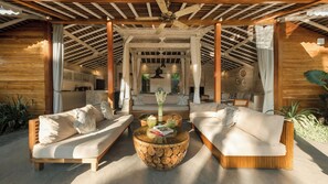 A spacious living area with a wooden ceiling, a central coffee table, and a sofa set. - Villa Taramille by Villa Finder (Kerobokan)