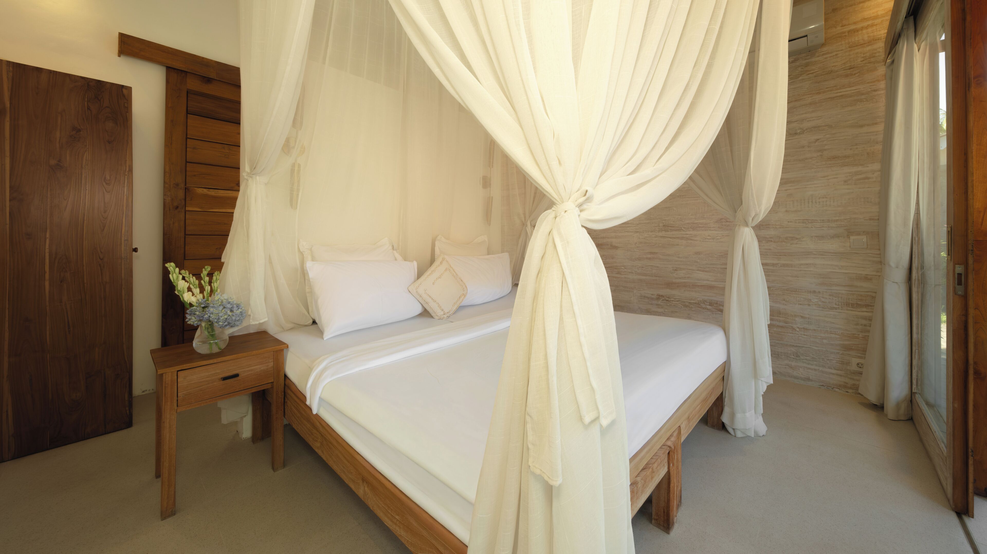 A bedroom with a wooden bed, white bedding, and a canopy.