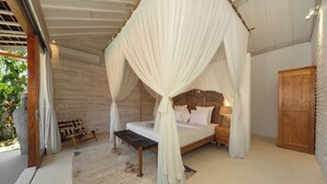 Ein Zimmer mit einem Bett, das unter einem Baldachin steht, einer Holzbank, einem Nachttisch und einem Kleiderschrank.