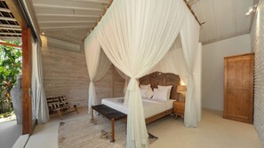 A room with a bed under a canopy, a wooden bench, a nightstand, and a wardrobe. - Villa Taramille by Villa Finder (Kerobokan)