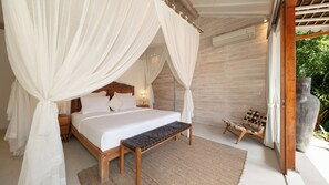 Een slaapkamer met een hemelbed, een bankje en uitzicht op groen.