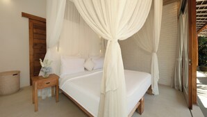 Un dormitorio con cama con dosel, cabecero de madera, mesita de noche con un florero y una pared de ladrillo.