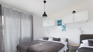 A modern bedroom with a large bed, a side table, and a hanging pendant light. - Prskalo by Interhome (Omiš)