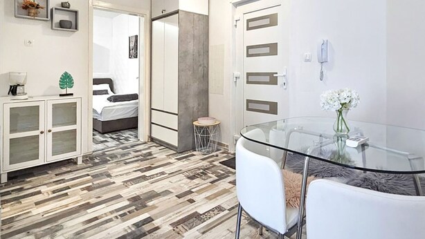 A modern, well-lit room with a bed, a glass dining table, and a white cabinet. - Prskalo by Interhome (Omiš)