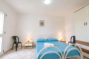 A bedroom with a bed, bedside tables, chairs, a wardrobe, and a framed picture on the wall.