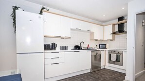 Une cuisine moderne avec des meubles blancs, un lave-vaisselle encastré, un four à micro-ondes et une cuisinière.
