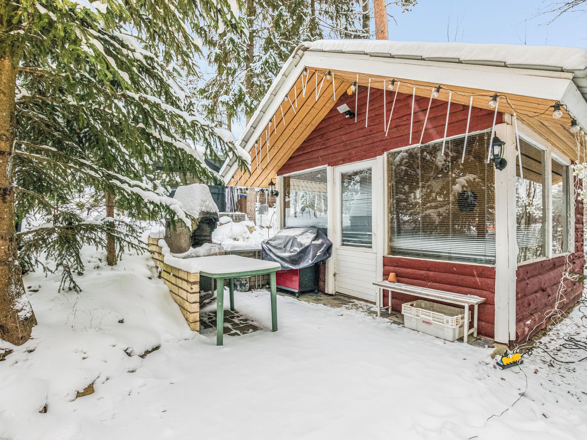 A snow-covered outdoor area with a wooden structure, a table, and a bench.