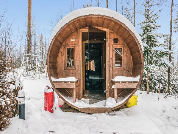 A wooden cabin with a circular entrance, two windows, and a bench outside.