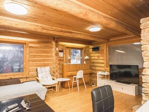 A log cabin interior with a sofa, chairs, a TV, and a fireplace.