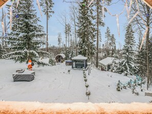 Un espacio exterior cubierto de nieve con una estructura de madera, posiblemente una cabaña, rodeada de árboles cargados de nieve.