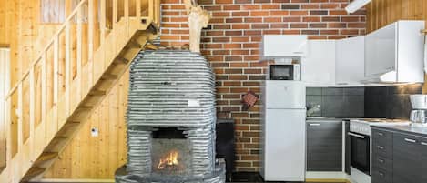 A kitchen with a stone fireplace, wooden staircase, and modern appliances.
